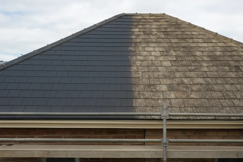 A hipped roof half re-slated, new dark slate beside weathered slate, scaffold at the eave — slate roof replacement, Hobart. Illustrative example.